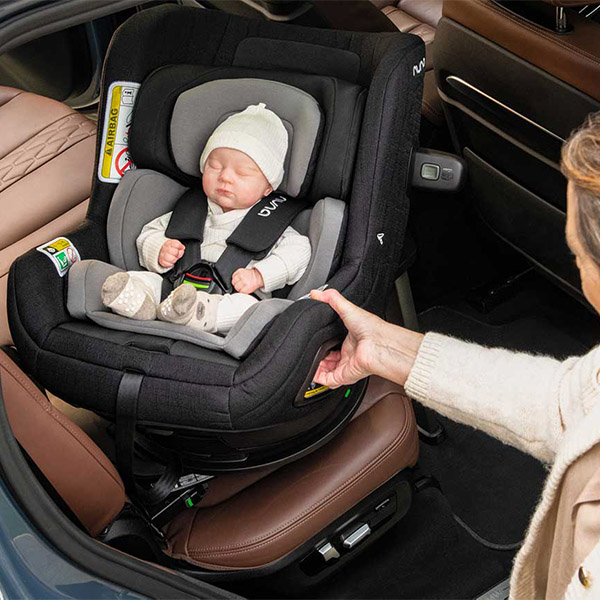 Mutter holt ihr Baby mit Babyschale aus dem Auto